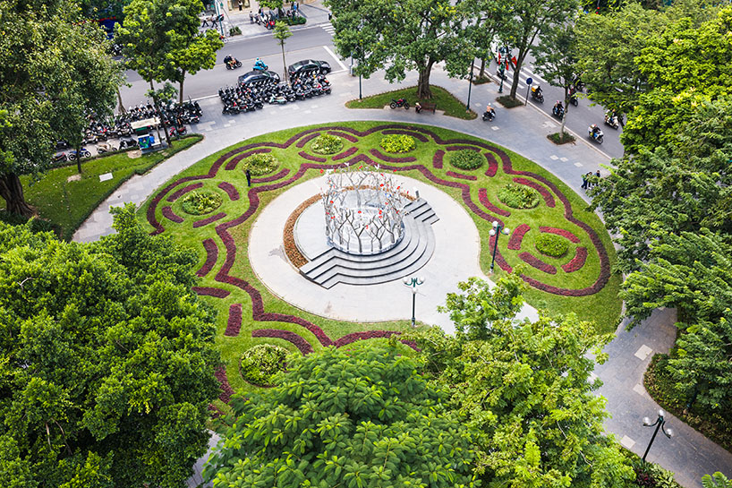 a circle of mirroring steel branches composes a luminous forest in hanoi’s public realm