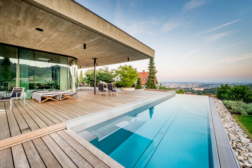 caramel architects' poolside family home overlooks city in austria