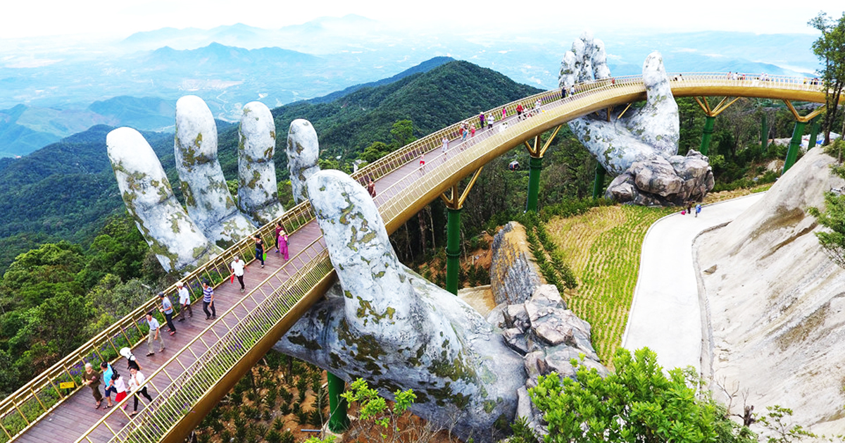 a giant pair of hands lift vietnam's da nang golden bridge into the sky