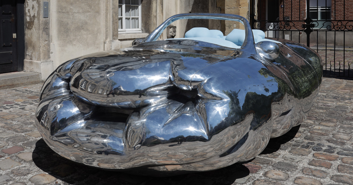 erwin wurm parks his fat car, narrow house, and big coat across the french city of le havre