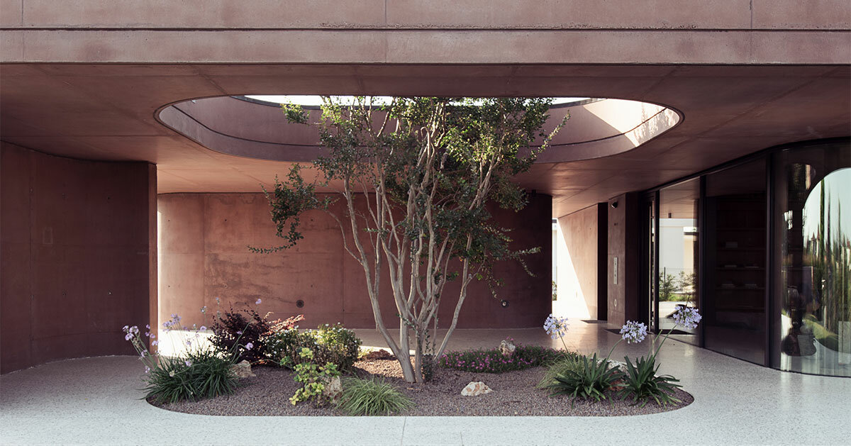 La residenza in cemento rosa di MIDE architetti si curva attorno a una rigogliosa vegetazione in Italia