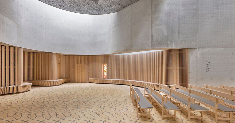 fluid concrete shell wraps timber interiors of danish trekroner church