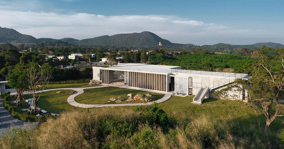 repetitive vertical fins enfold concrete structure embedded within thailand’s mountainscape