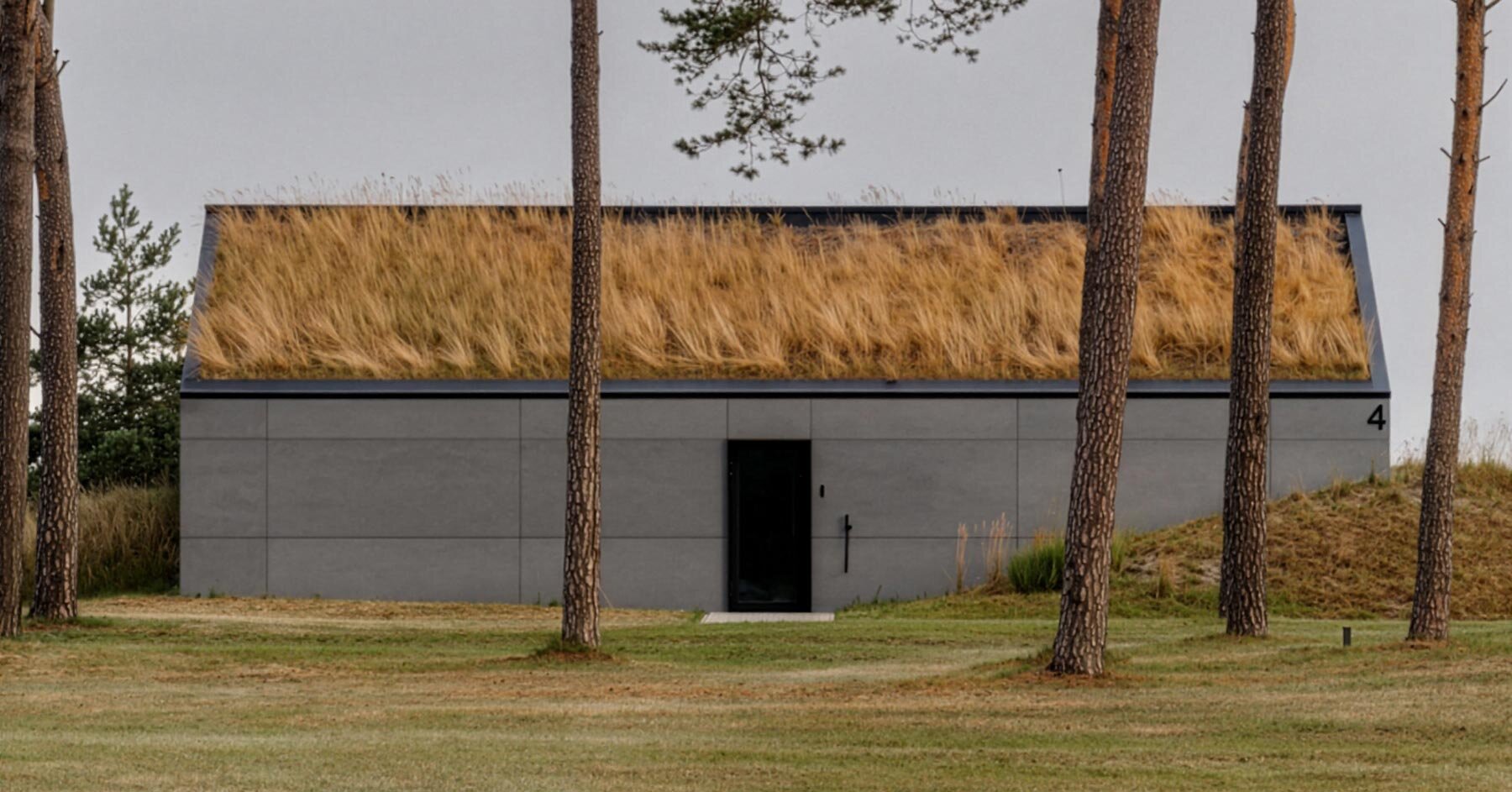grass-covered seaside family home repurposes abandoned soviet military bunkers in latvia