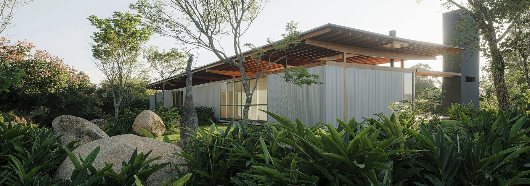 oversized boulders and native trees determine footprint of timber pavilion in brazil