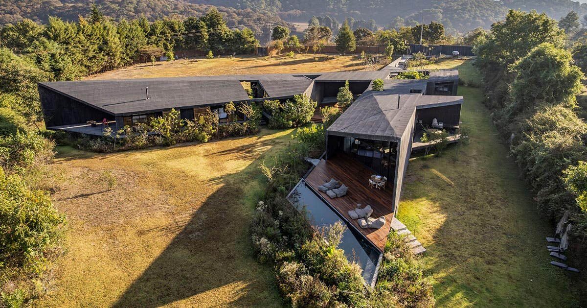 two intersecting volumes of black concrete carve mavra house into the mexican landscape