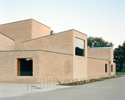raum architects builds monolithic cultural center in france using terracotta bricks + concrete