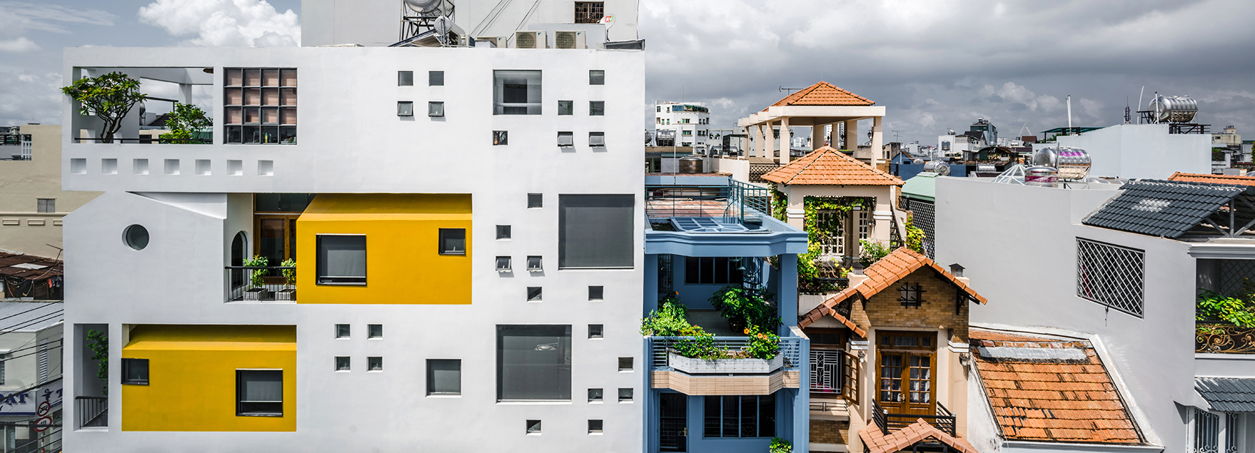 23o5 studio's HVB complex in vietnam comprises tree-filled voids and bright yellow volumes