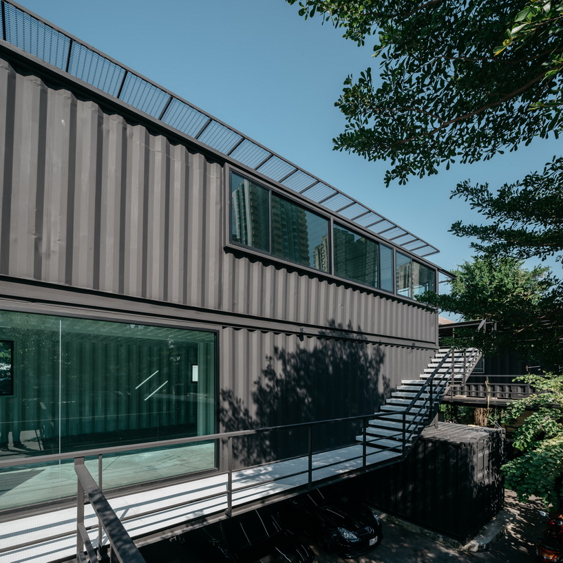 archimontage stacks shipping containers to form 'carcare' center in bangkok