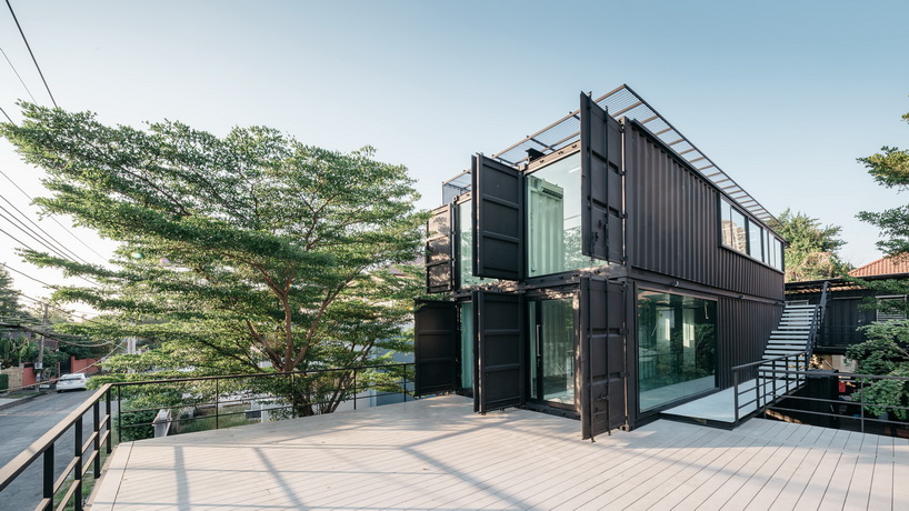 archimontage stacks shipping containers to form 'carcare' center in bangkok