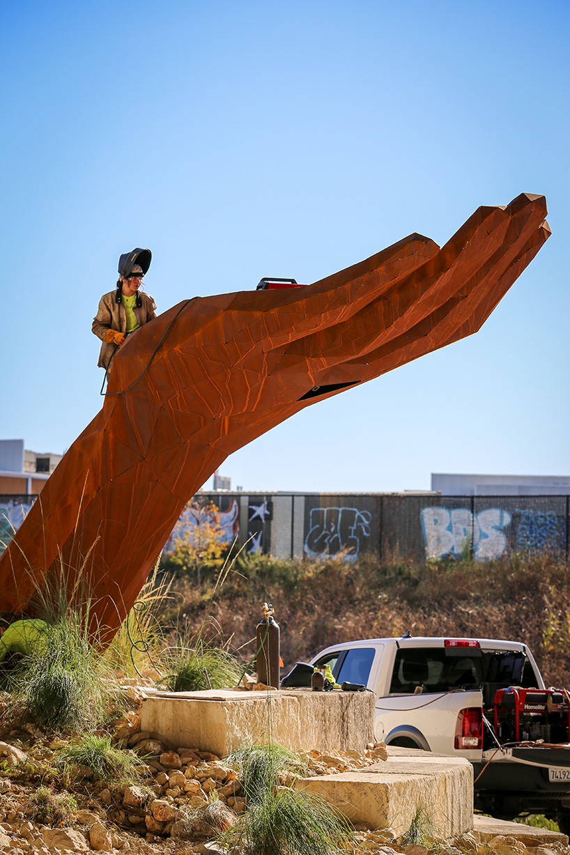 mark reigelman's oversized hand sculpture captures runoff water from overpass in texas