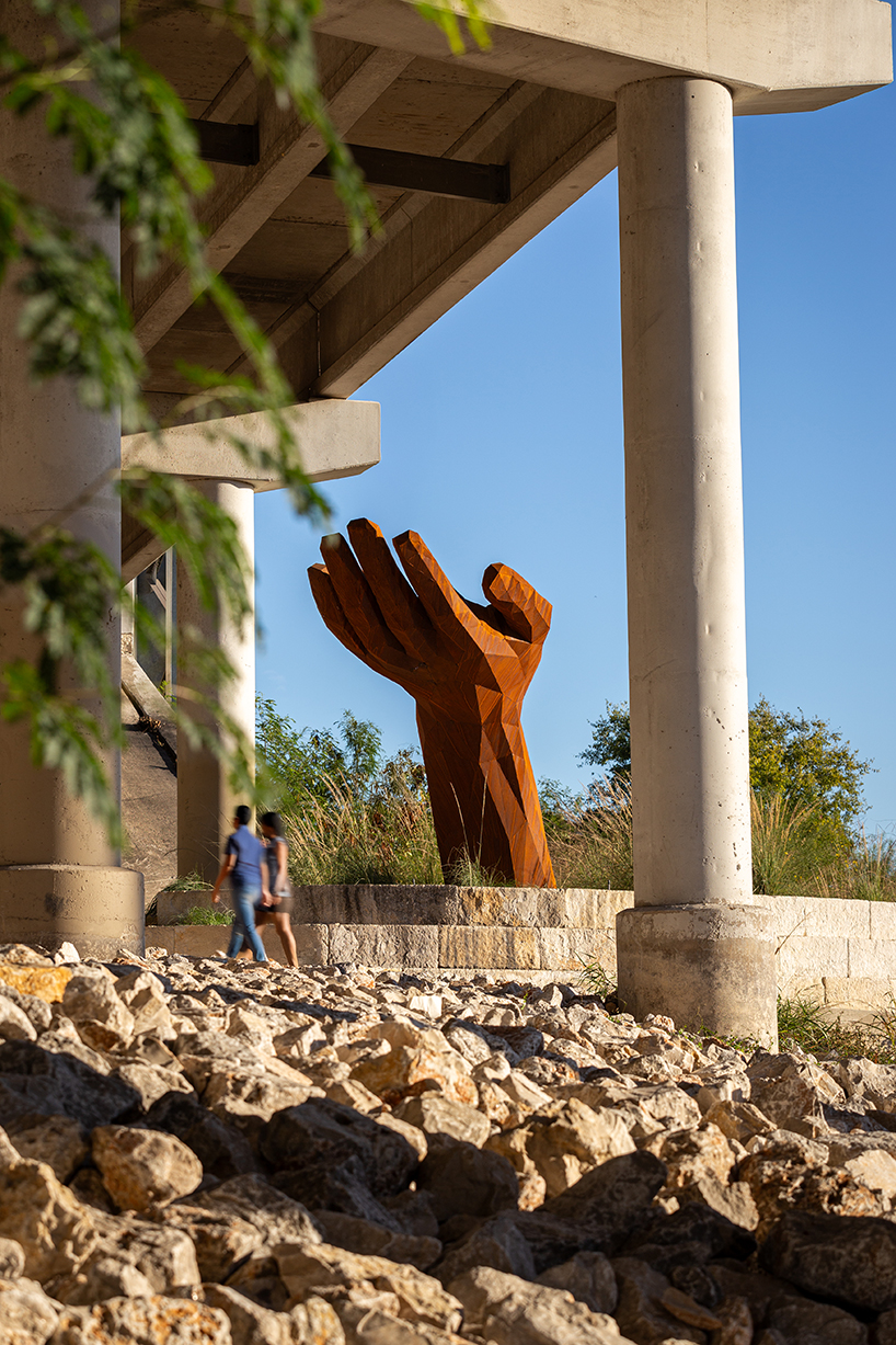 mark reigelman's oversized hand sculpture captures runoff water from overpass in texas