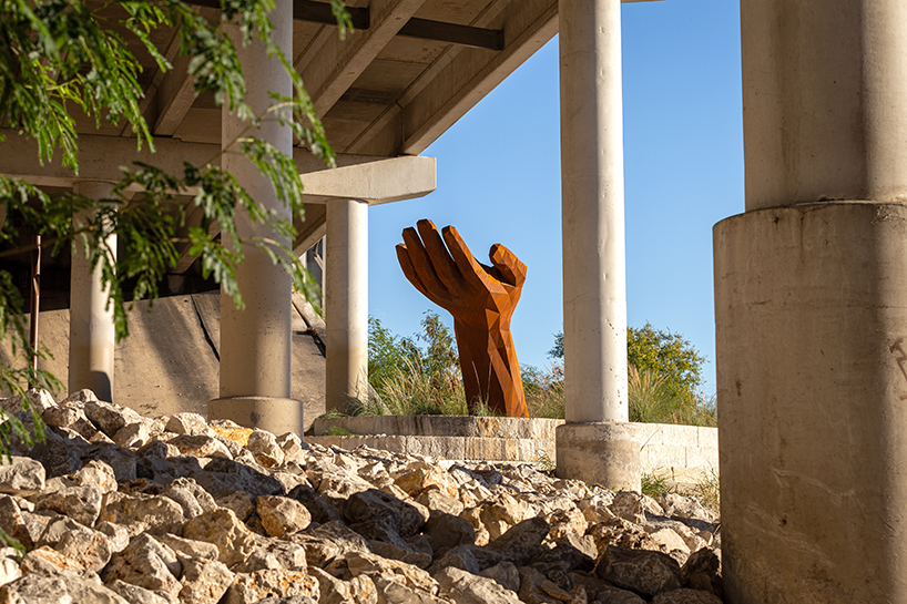 mark reigelman's oversized hand sculpture captures runoff water from overpass in texas