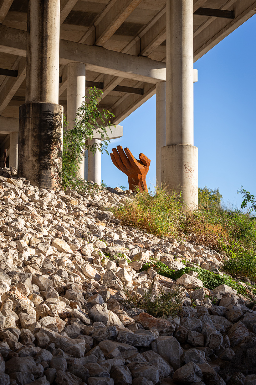 mark reigelman's oversized hand sculpture captures runoff water from overpass in texas