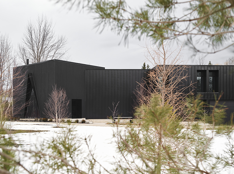 charred wood ski chalet by atelier RZLBD tucks into sloping terrain in rural canada