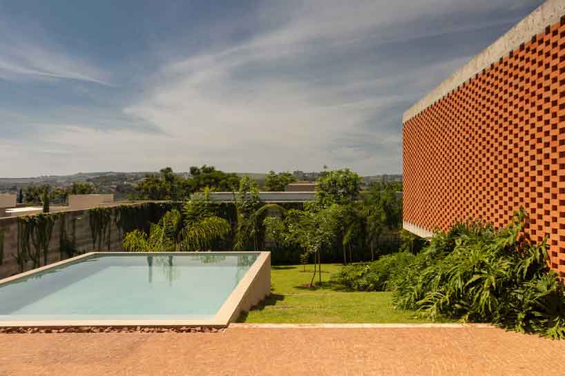perforated brick facade punctuates fernanda padula’s concrete house in brazil