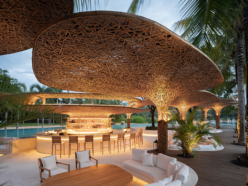 a cluster of bamboo canopies tops resort beach club by various associates amid china's coconut groves