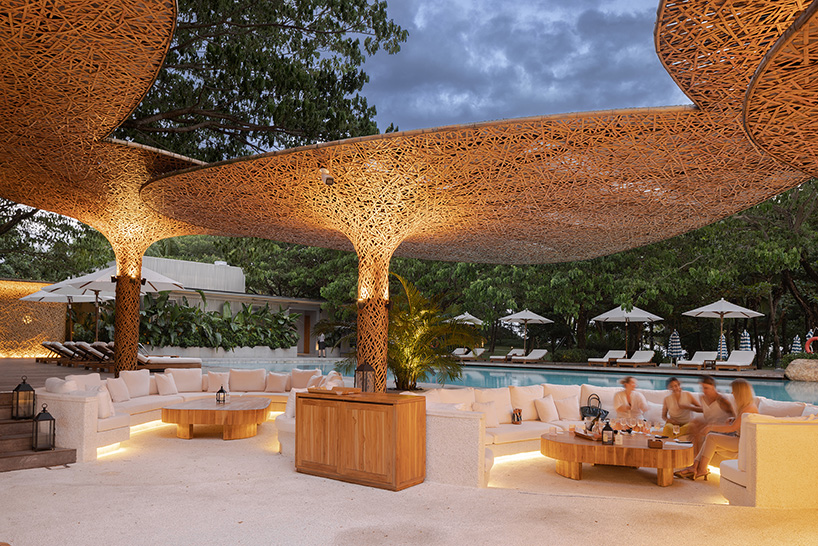 a cluster of bamboo canopies tops resort beach club by various associates amid china's coconut groves