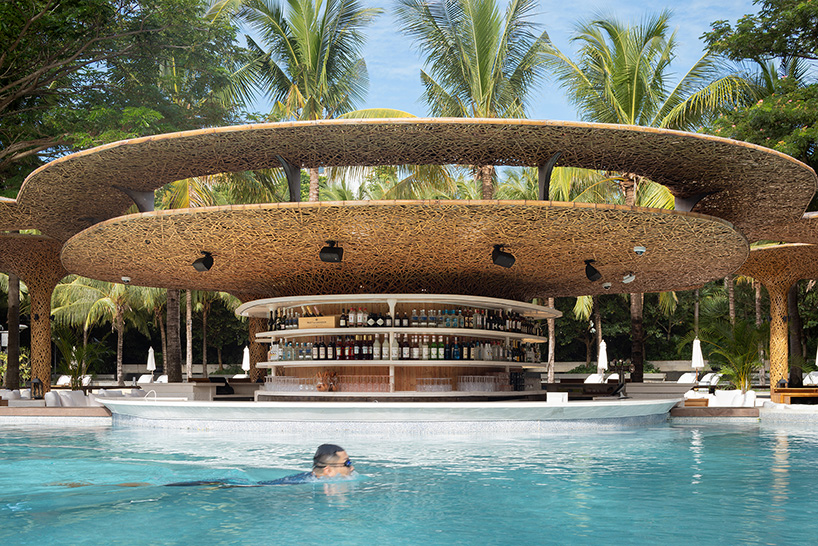 a cluster of bamboo canopies tops resort beach club by various associates amid china's coconut groves