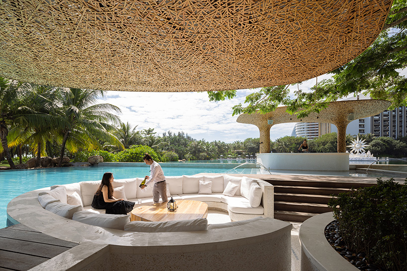 a cluster of bamboo canopies tops resort beach club by various associates amid china's coconut groves