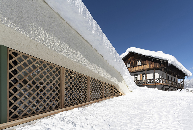 local larch wood + stone clad plasma studio's bistro anchored in dolomites' landscape