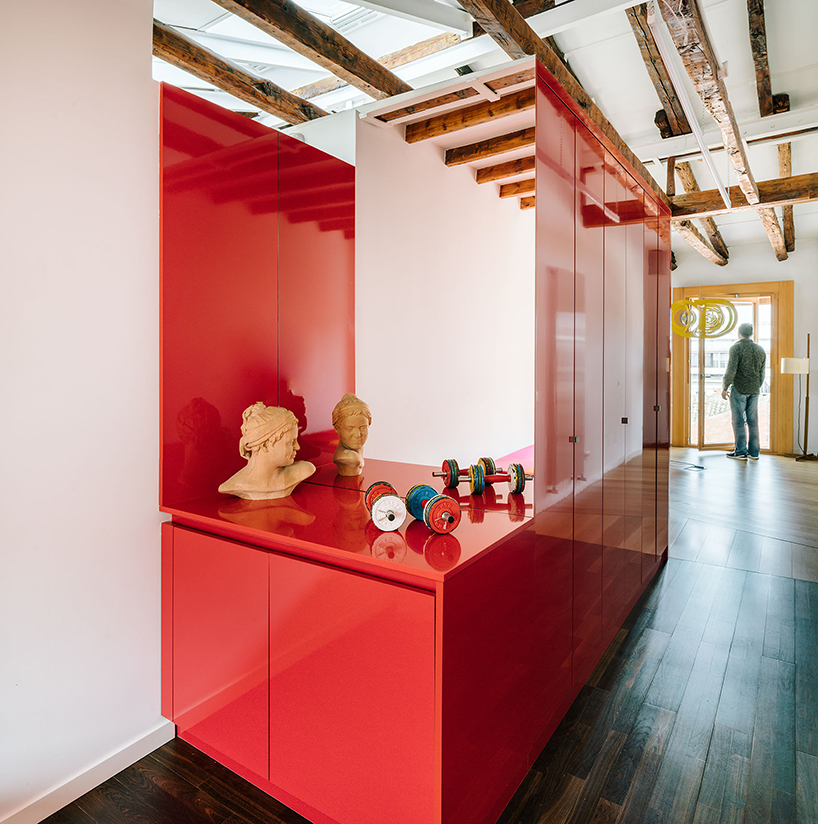 gon architects inserts a bright red, continuous furniture to articulate attic in madrid