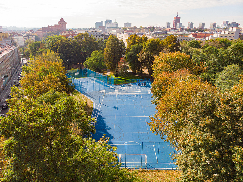 UGO completes a bright blue sports field in poznan, poland designboom