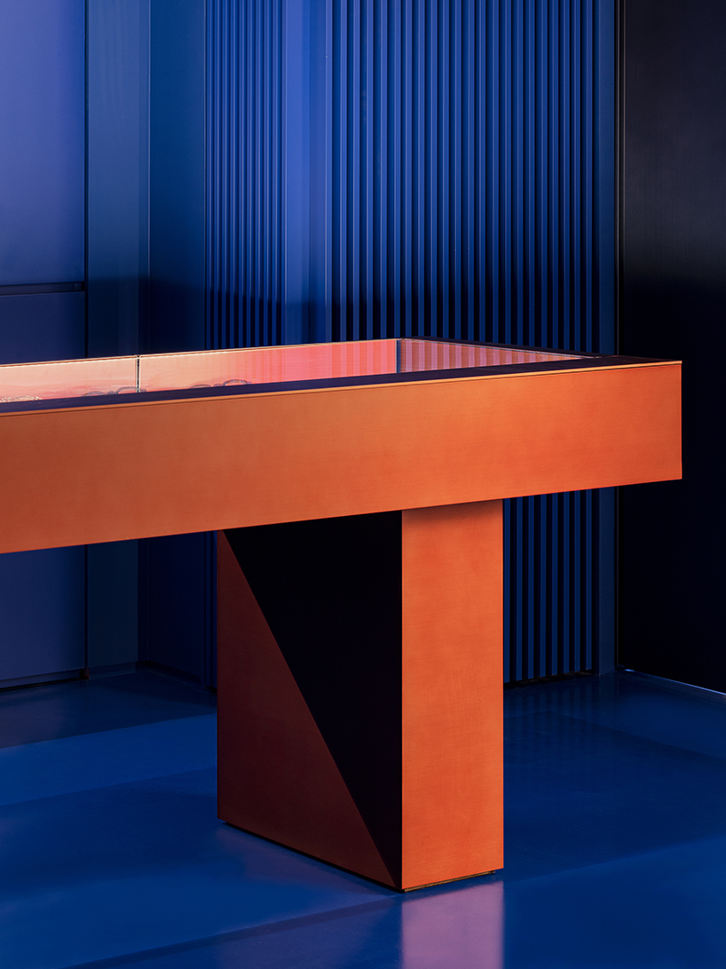 bold red stainless steel fixtures adorn blue eyewear store interior by WGNB in seoul