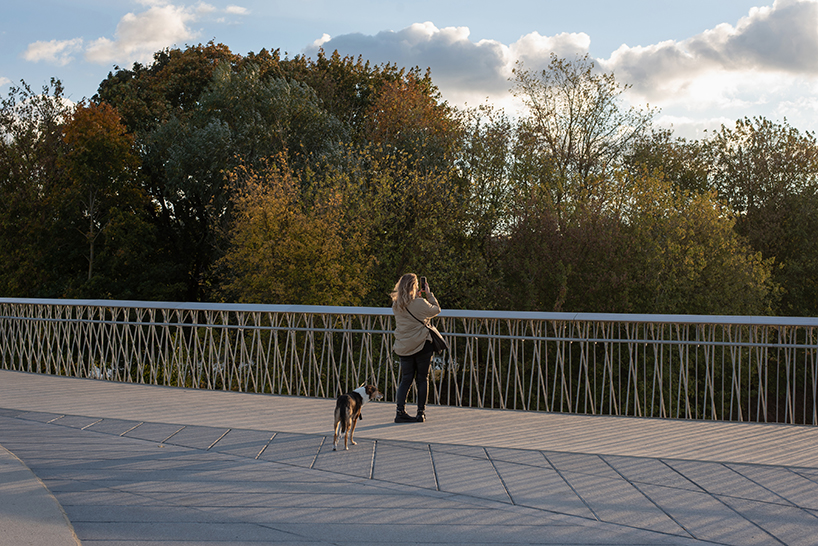 winding pedestrian bridge-plaza converges historic lithuanian city center with public park