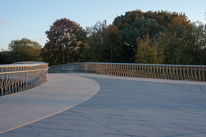 winding pedestrian bridge-plaza converges historic lithuanian city center with public park