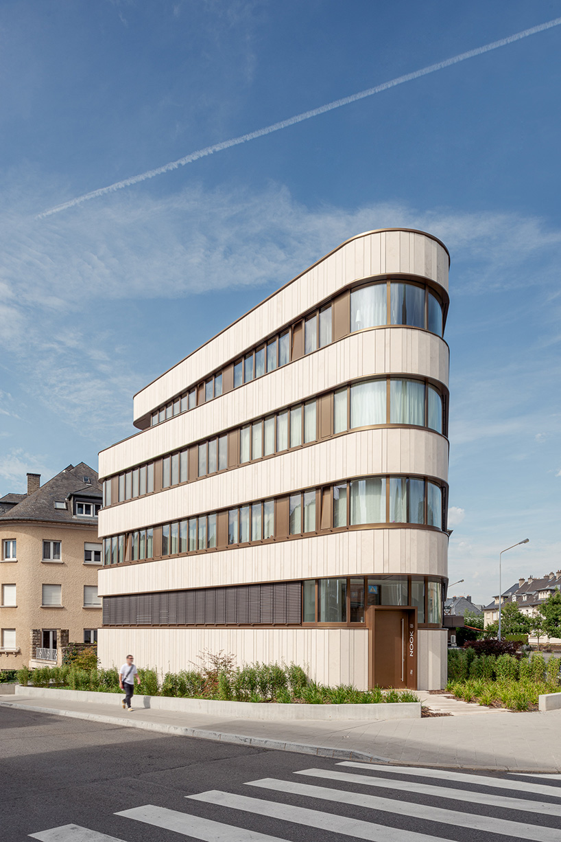 limestone and glass wrap around the curved facade of residential building in luxembourg