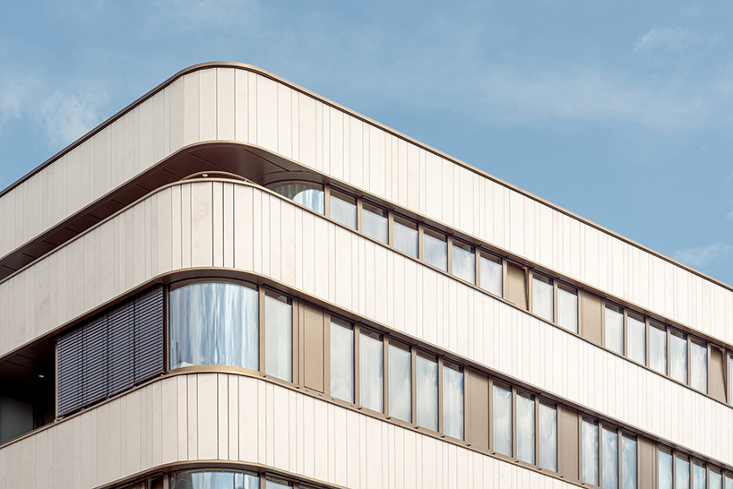 limestone and glass wrap around the curved facade of residential building in luxembourg