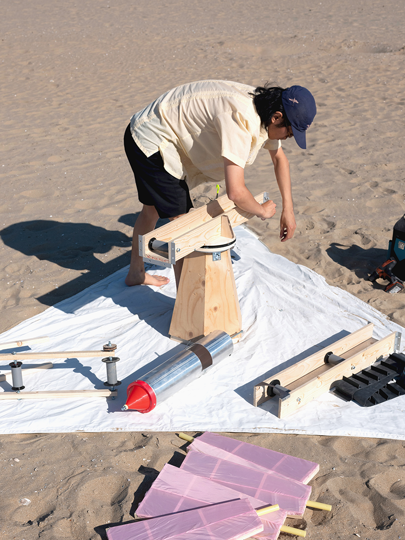 taiyi yu’s windmill on the beach rotates in the breeze to create an imprint in the sand