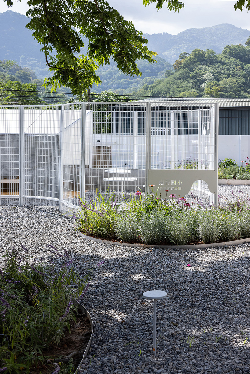 curved white fence by studio whispace + architects encloses chicken coop and herb zone in school in taiwan 