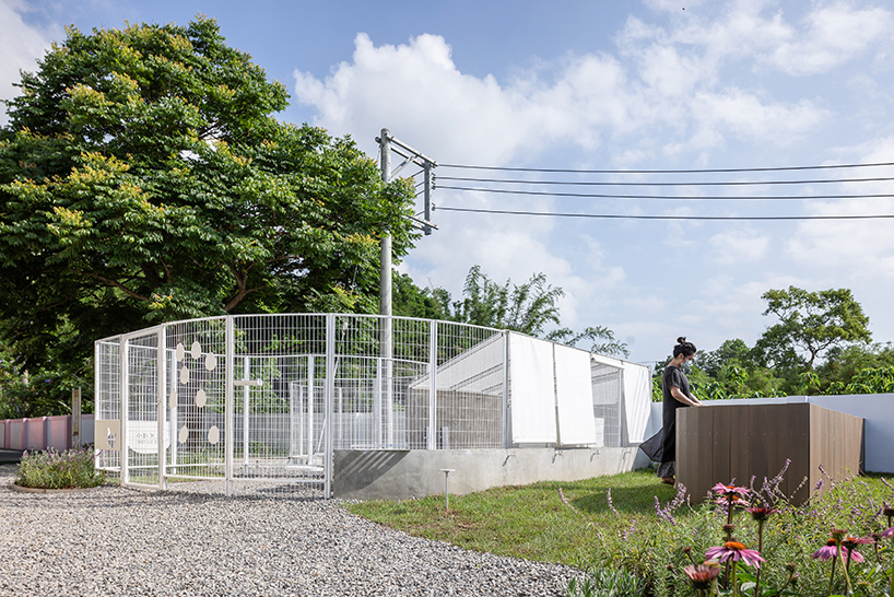 curved white fence by studio whispace + architects encloses chicken coop and herb zone in school in taiwan 