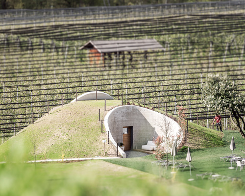grass-covered sauna by noa* emerges from the valley landscape in italy