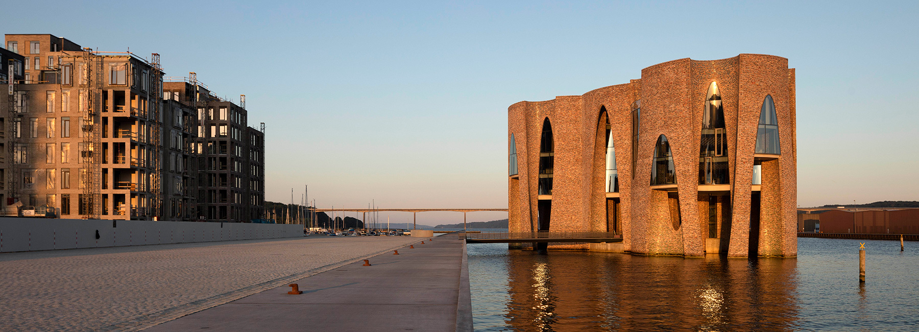 olafur eliasson's first building is a curved brick, semi-submerged scheme in denmark