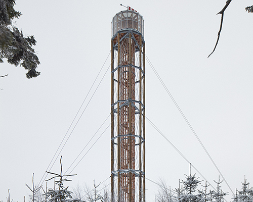 a timber lookout tower rises above the forested mountains of a czech ski area