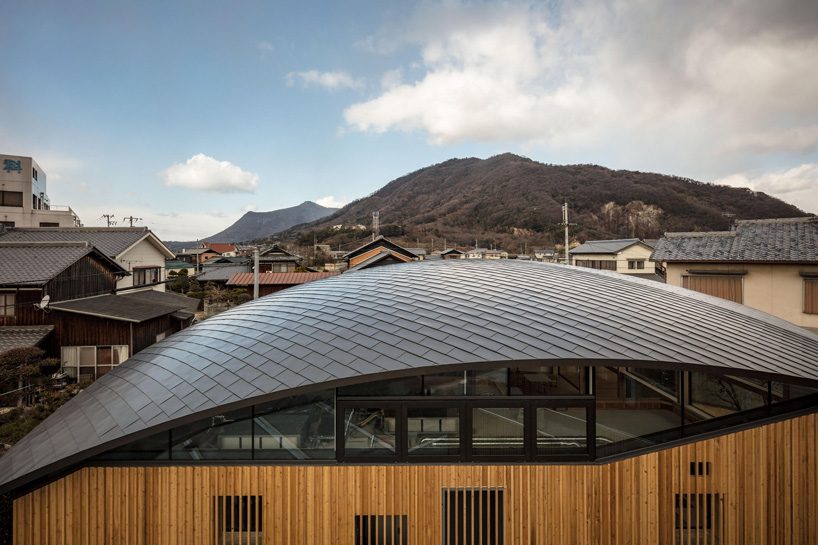 curved wood lattice roof hangs above nasca's blue sky nursery school in japan - 5