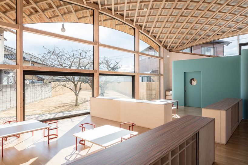 curved wood lattice roof hangs above nasca's blue sky nursery school in japan - 9