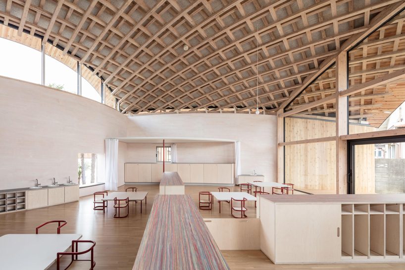 curved wood lattice roof hangs above nasca's blue sky nursery school in japan - 8