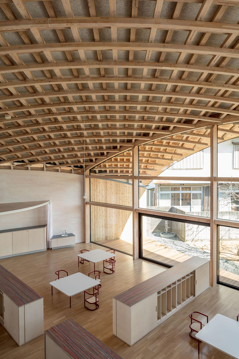 curved wood lattice roof hangs above nasca's blue sky nursery school in japan - 7