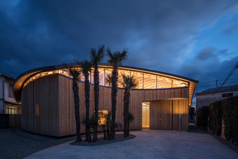curved wood lattice roof hangs above nasca's blue sky nursery school in japan - 13