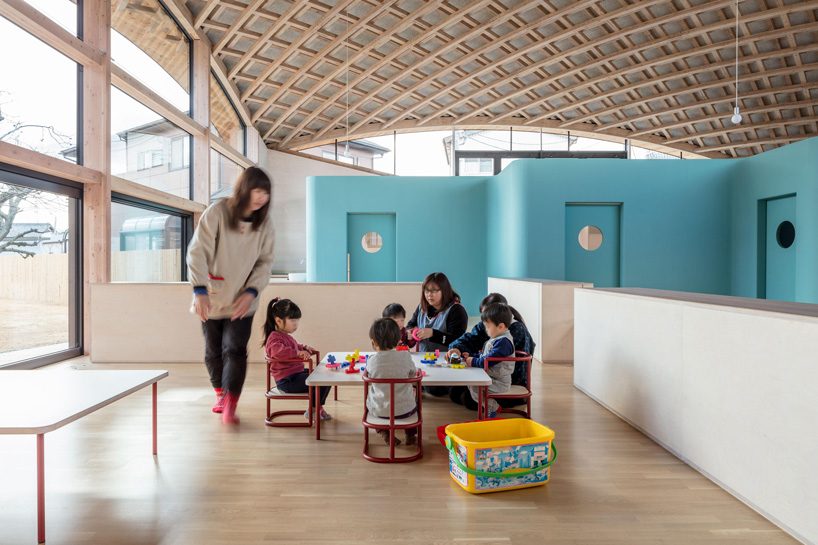 curved wood lattice roof hangs above nasca's blue sky nursery school in japan - 12