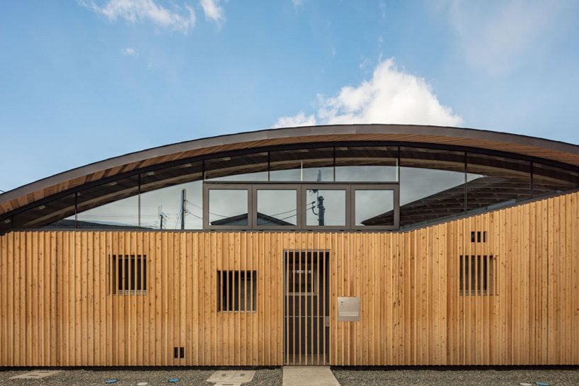 curved wood lattice roof hangs above nasca's blue sky nursery school in japan - 1