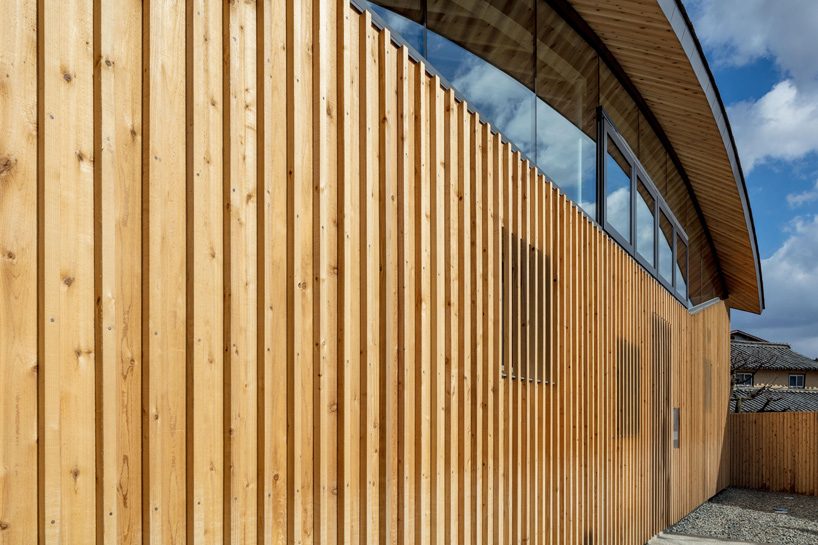 curved wood lattice roof hangs above nasca's blue sky nursery school in japan - 2