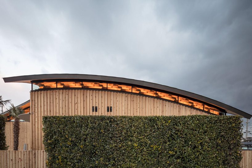 curved wood lattice roof hangs above nasca's blue sky nursery school in japan - 4