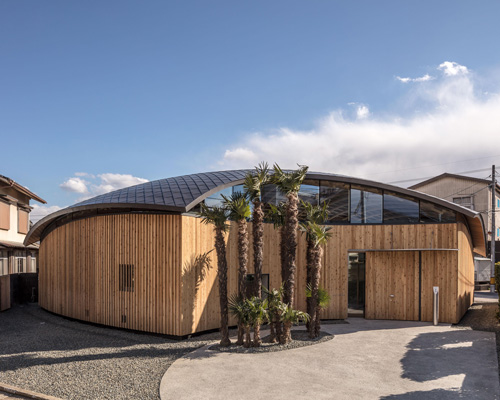 curved wood lattice roof hangs above nasca's blue sky nursery school in japan
