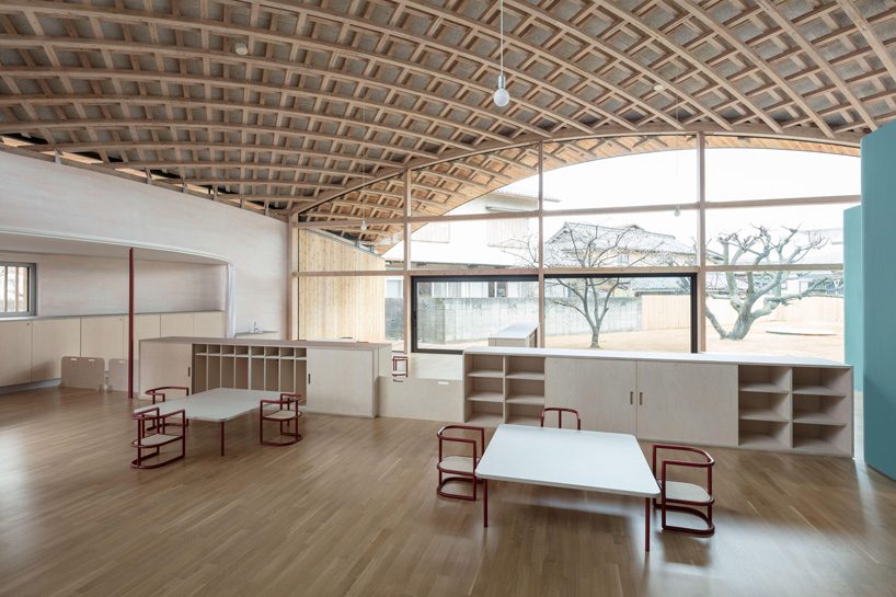 curved wood lattice roof hangs above nasca's blue sky nursery school in japan - 11