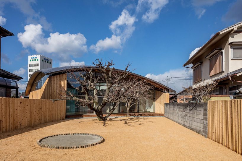 curved wood lattice roof hangs above nasca's blue sky nursery school in japan - 6